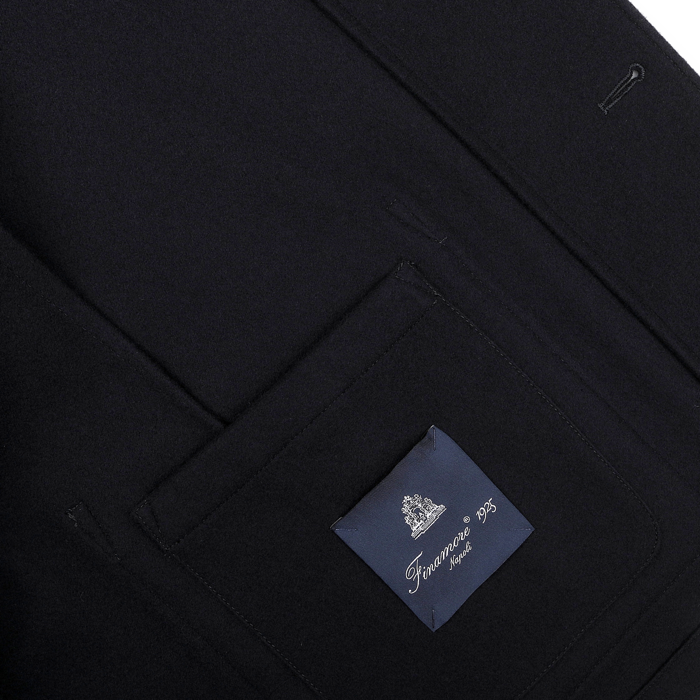 Close-up of a navy blue blazer pocket with a label reading "Finamore," seamlessly blending classic design with the modern touch of patch pockets.