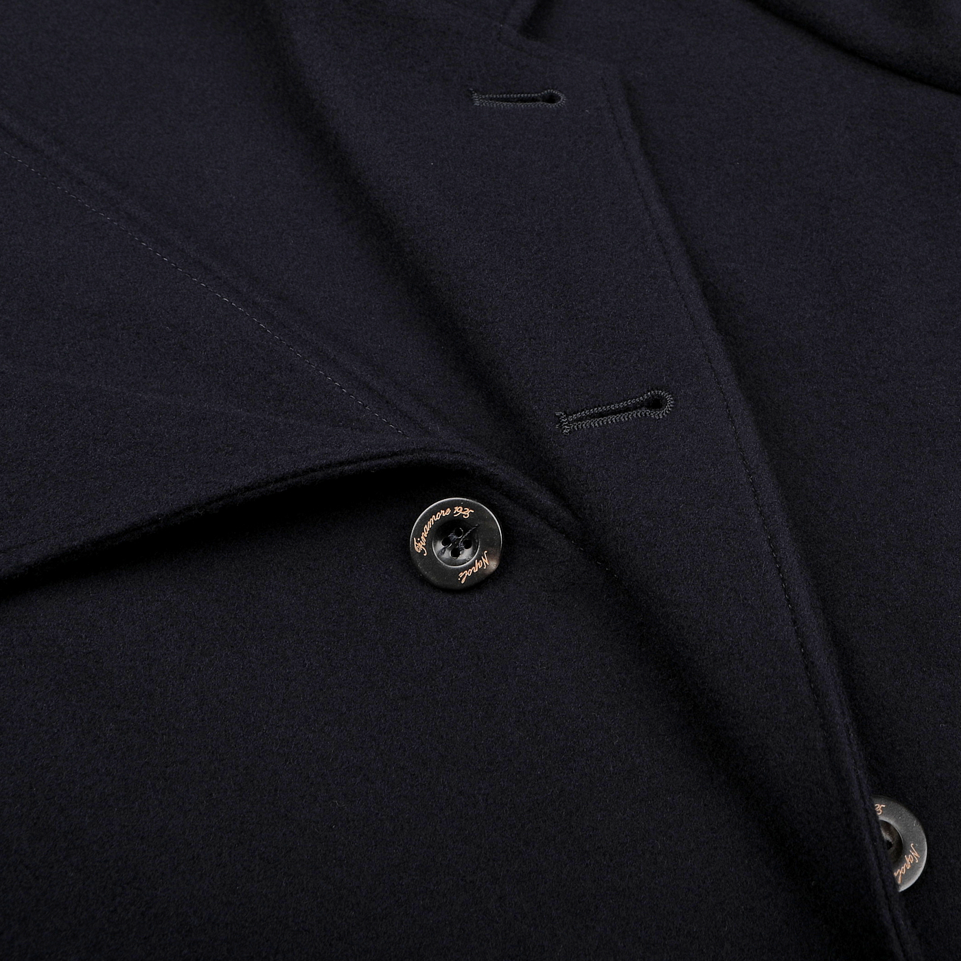 Close-up of a navy blue boiled wool casual blazer highlighting a partially open flap, button details, and its sleek patch pockets.