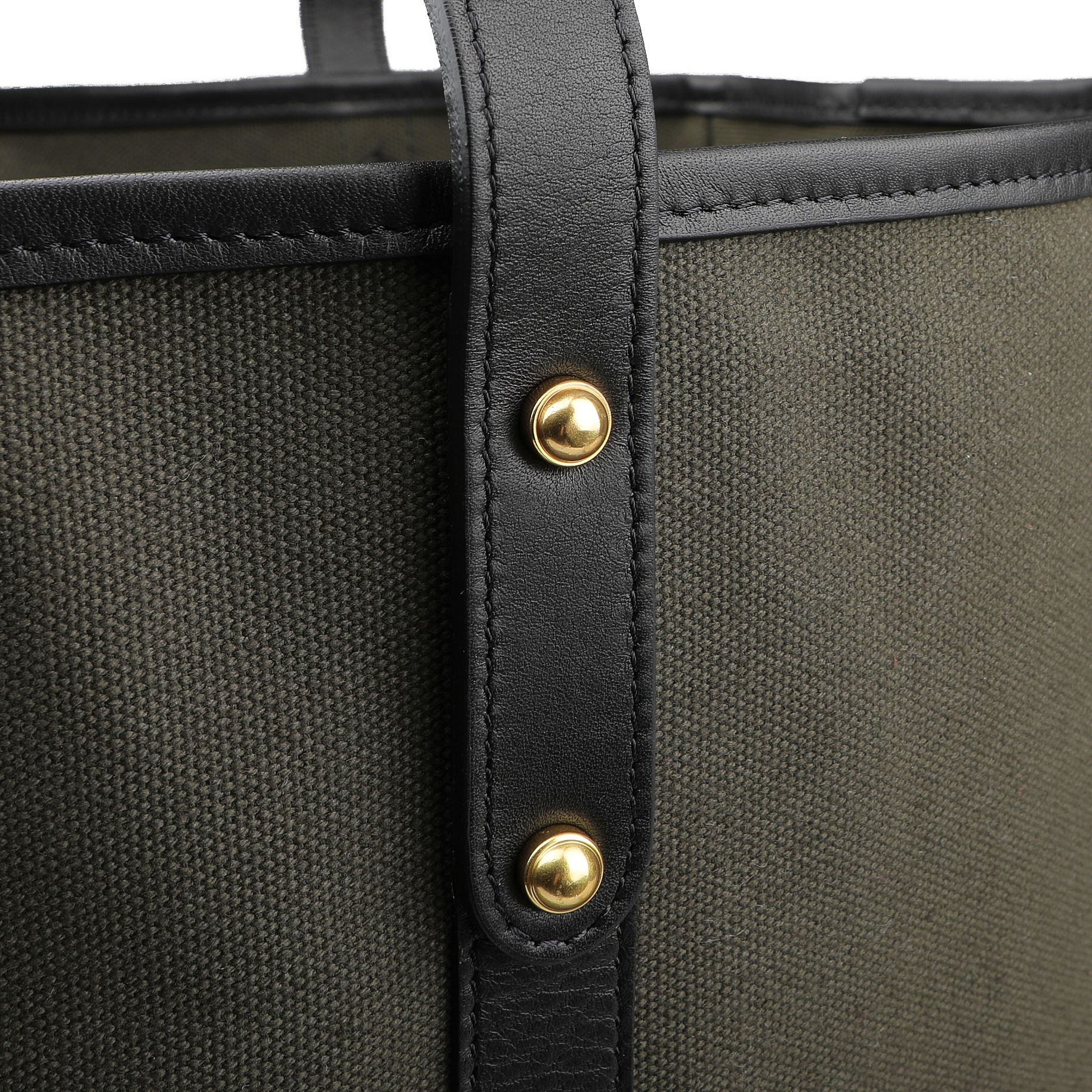 Close-up of a corner of the Army Green Canvas Tumbled Leather Market Tote Bag by Frank Clegg, showcasing dark green cotton canvas with black leather trimmings and gold rivet detailing.