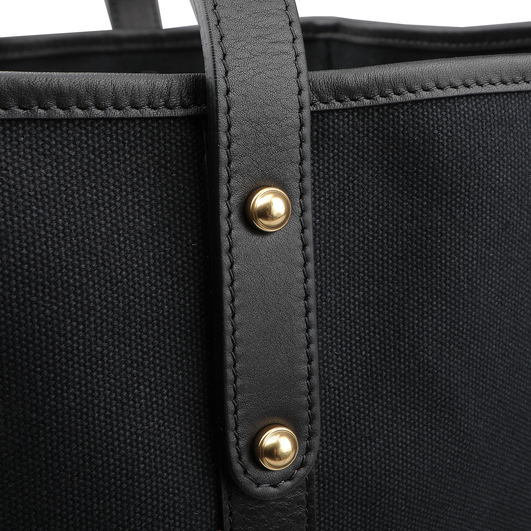 Close-up of Frank Clegg's Black Canvas Tumbled Leather Market Tote Bag, featuring leather trimmings, a sleek leather strap, and two brass studs.