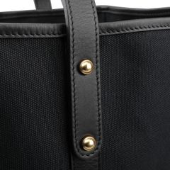 Close-up of Frank Clegg's Black Canvas Tumbled Leather Market Tote Bag, featuring leather trimmings, a sleek leather strap, and two brass studs.