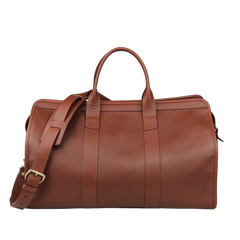 The Frank Clegg Chestnut Tumbled Leather Signature Travel Duffle boasts double handles and an adjustable strap, perfect for those seeking handcrafted quality against a neutral backdrop.