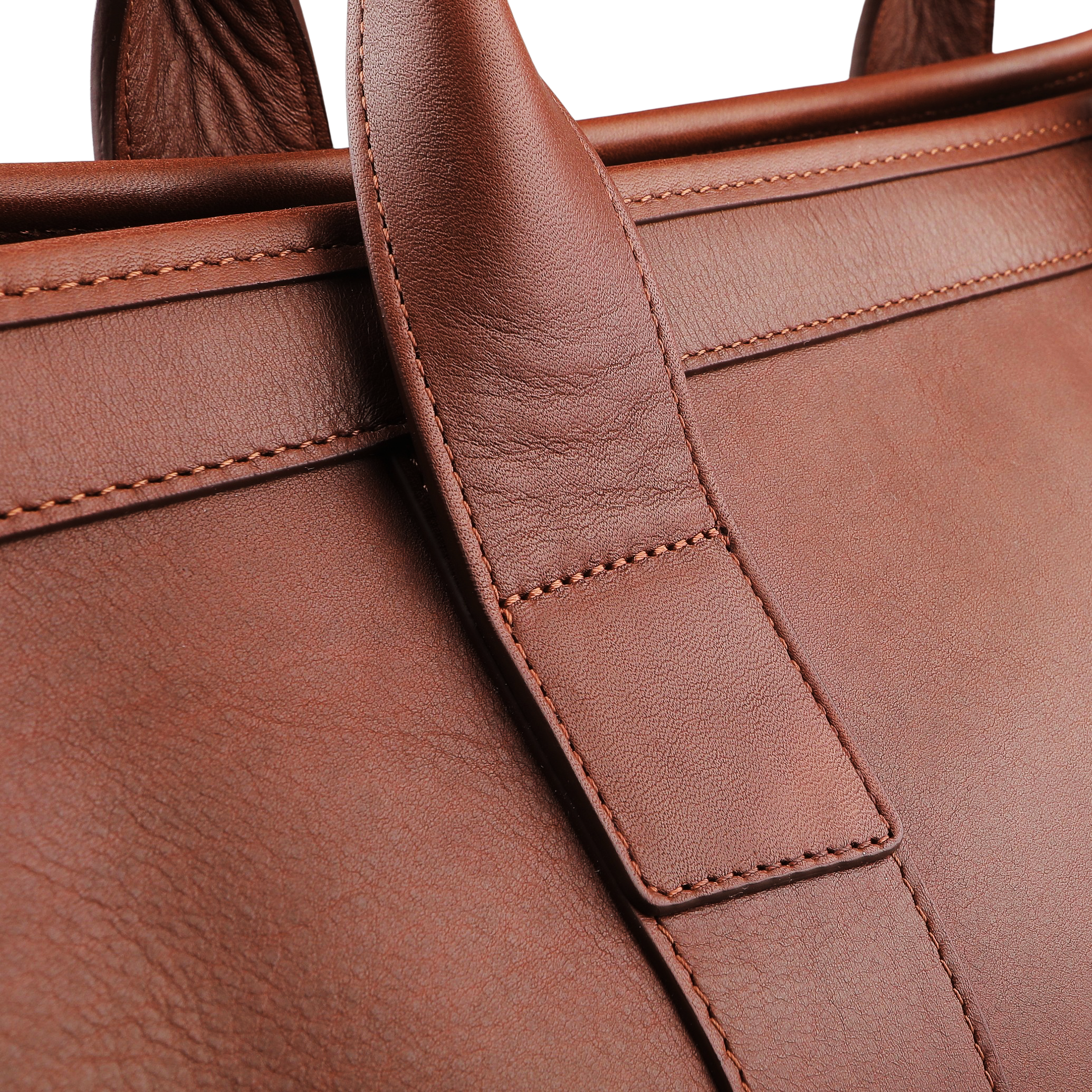 A close-up of the Chestnut Tumbled Leather Small Travel Duffle by Frank Clegg showcases intricate stitching and texture on the handle and body.