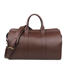 The Frank Clegg Chocolate Harness Belting Leather Signature Duffle is a luxury travel bag with handles and a shoulder strap.