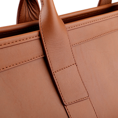 Close-up of Frank Clegg's Cognac Harness Leather Small Travel Duffle, showcasing the intricate stitching on the handle and body.