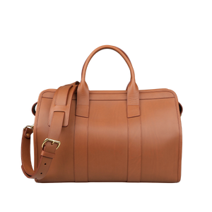 The Cognac Harness Leather Small Travel Duffle by Frank Clegg is a brown leather weekend bag crafted from harness belting leather, featuring handles and an adjustable shoulder strap for convenience and style.