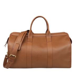 The Cognac Tumbled Leather Signature Duffle by Frank Clegg, a luxurious handcrafted brown leather bag with a shoulder strap and two handles, rests on a plain background.