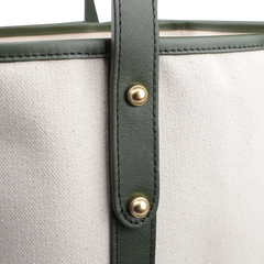 Close-up of the Frank Clegg Natural Canvas Tumbled Leather Market Tote Bag, featuring green leather trimmings and brass rivets.