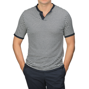 A person stands confidently against a plain background wearing a G.R.P Blue Ecru Striped Linen Henley T-Shirt, featuring a slim fit and dark collar, paired with dark pants.