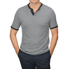 A person stands confidently against a plain background wearing a G.R.P Blue Ecru Striped Linen Henley T-Shirt, featuring a slim fit and dark collar, paired with dark pants.