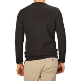 A person wearing a Brown Melange Wool Crewneck Sweater from G.R.P and beige pants, shown from the back with their left hand slightly visible.