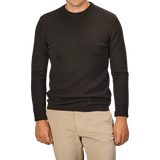 A man wearing a G.R.P Brown Melange Wool Crewneck Sweater and beige pants, facing forward with arms relaxed at his sides. His head is partially out of the frame.