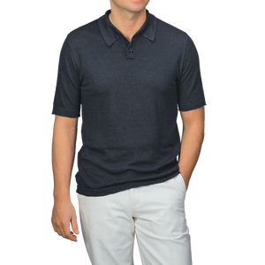 A man poses with one hand in his pocket against a plain background, wearing a dark blue linen polo shirt by G.R.P paired with light-colored pants.