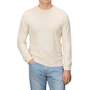 A person wearing a G.R.P Ecru Beige Linen Crewneck Sweater with light blue jeans, standing against a plain background.