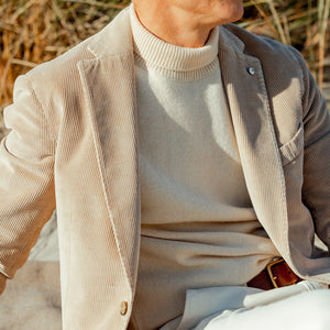 A man wearing a Ecru Wool Cashmere Mock Neck Sweater by G.R.P and white pants.