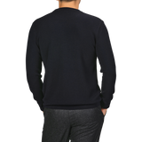 A person is standing with their back to the camera, wearing a Night Blue Wool Crewneck Sweater from G.R.P and gray pants.