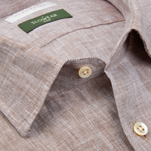 Close-up of a textured Glanshirt brown melange linen regular fit shirt with a collar and buttons, displaying a label with the brand "slowear".