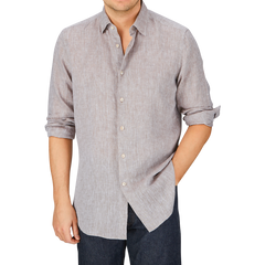 A person wearing a Glanshirt Brown Melange Linen Regular Shirt with one hand in their pocket and the sleeves rolled up.