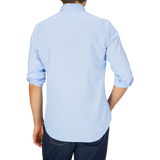 Man seen from behind wearing a Glanshirt light blue pure cotton oxford shirt with mother-of-pearl buttons and dark blue jeans.