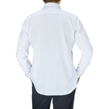 A person standing with their back to the camera, wearing a Glanshirt White Cotton Oxford Regular Shirt with mother-of-pearl buttons and black pants.