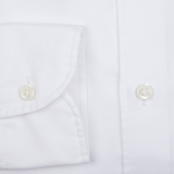 Close-up of a Glanshirt white cotton oxford regular shirt detailing a buttoned sleeve and placket with mother-of-pearl buttons.