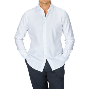 Man wearing a Glanshirt White Cotton Oxford Regular Shirt with mother-of-pearl buttons and dark trousers.