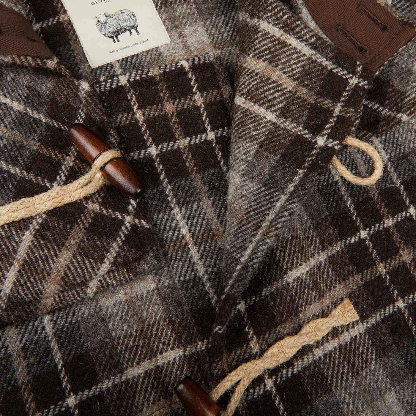 A close up of a De Bonne Facture Brown Undyed Shepherds Check Wool Duffle Coat.