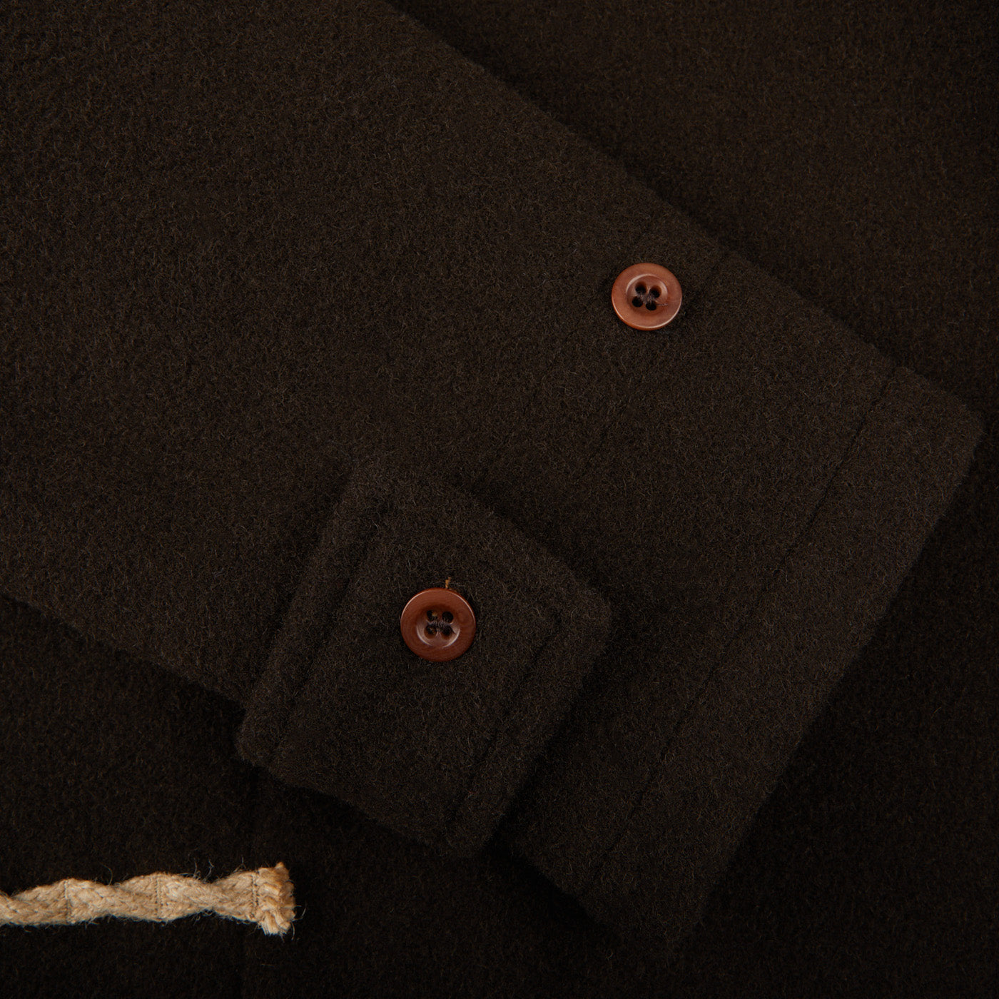 A close up of a Dark Brown Wool Monty Duffle Coat by Gloverall with buttons.