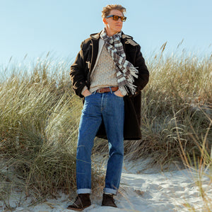 A man standing on a sand beach wearing a Gloverall Dark Brown Wool Monty Duffle Coat.