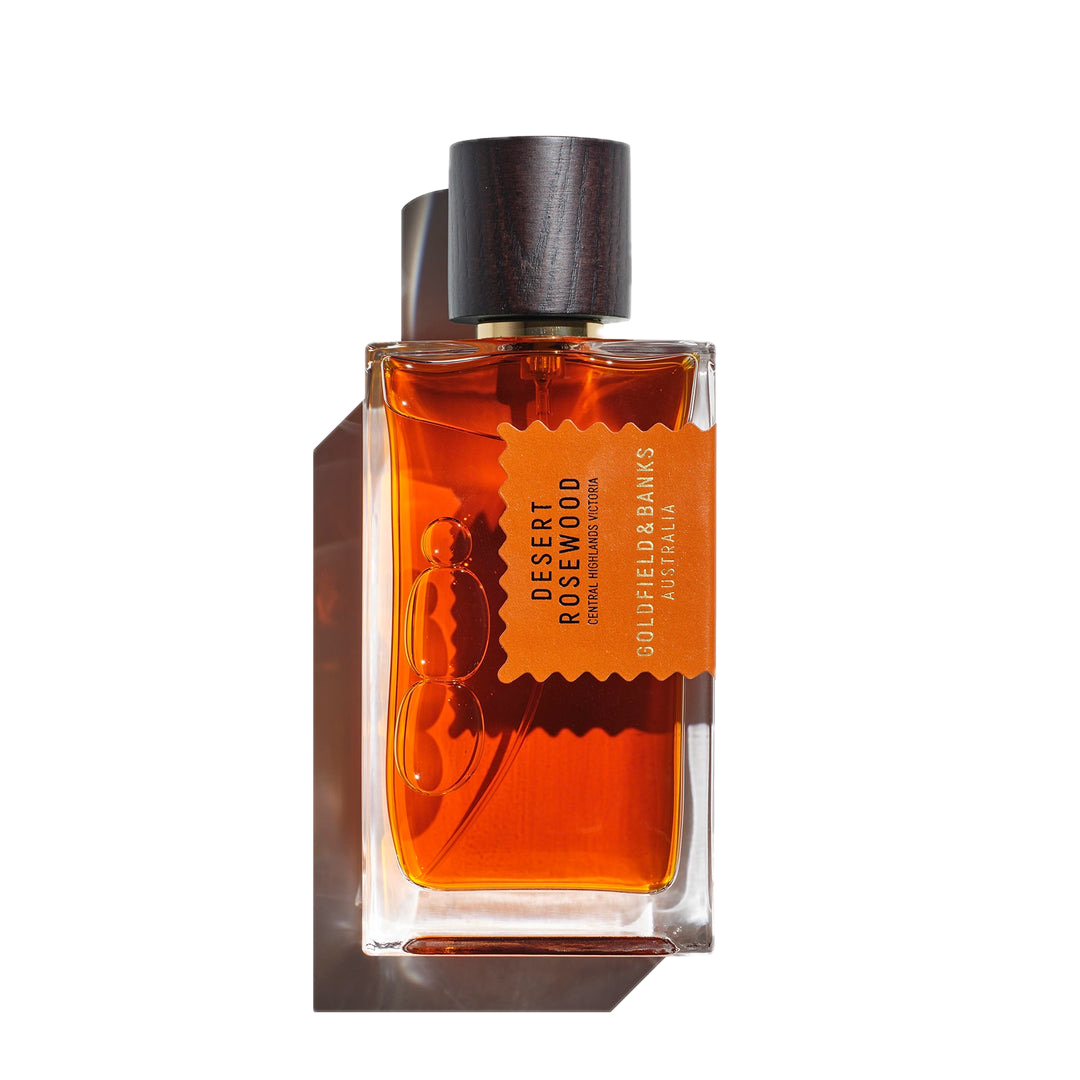 Goldfield & Banks' "Desert Rosewood 100ml Eau de Parfum" comes in a rectangular glass bottle with a dark wooden cap, conveying a luxurious woody fragrance.