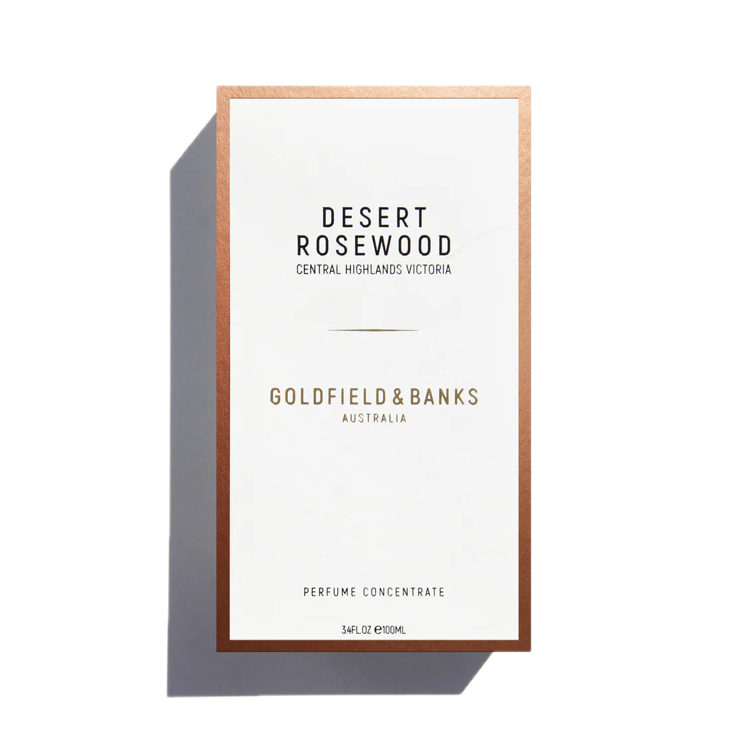 The front view of a Goldfield & Banks Desert Rosewood 100ml Eau de Parfum box reveals an exotic blend, with a design featuring a white background and a copper border, suggesting the woody fragrance within.