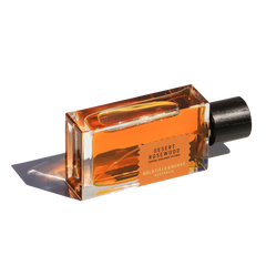 The Desert Rosewood 100ml Eau de Parfum by Goldfield & Banks is presented in a sleek rectangular glass bottle, showcasing its exotic blend with an amber-hued liquid and a sophisticated black cap, displayed elegantly against a white background.