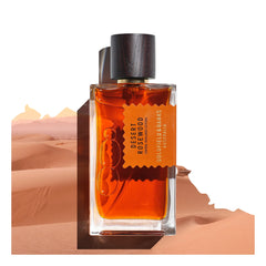 A Goldfield & Banks Desert Rosewood 100ml Eau de Parfum bottle is gracefully positioned against a desert landscape background, suggesting an exotic blend.