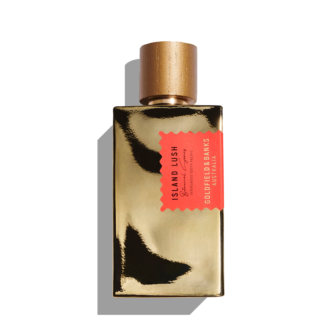 A gold bottle of Goldfield & Banks Island Lush 100ml Eau De Parfum, adorned with a red tag, is set against a white background, embodying the exoticism of contemporary woods and the captivating essence of South Pacific Sandalwood.