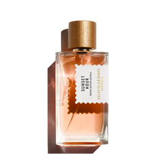 A bottle of Goldfield & Banks Sunset Hour 100ml Eau De Parfum features a gold cap and a peach-colored liquid inside, offering an exquisite blend of spicy notes with subtle floral hints for a unique olfactory experience.