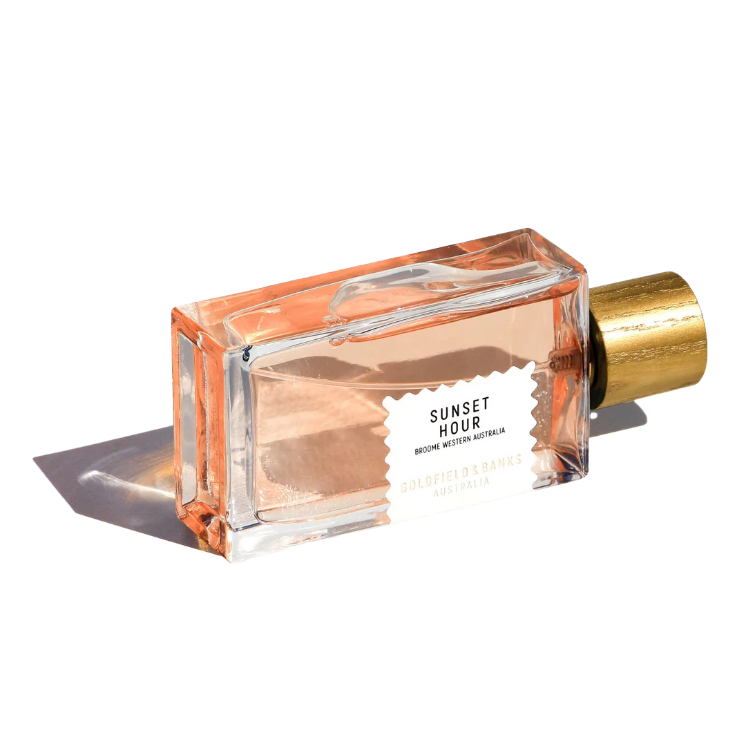 The "Sunset Hour" 100ml Eau De Parfum by Goldfield & Banks, topped with a golden cap and artfully angled on a white background, releases a citrus fragrance that embodies the sophistication of twilight elegance.