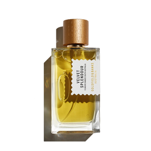 A clear glass bottle of Velvet Splendour 100ml EdP reveals its golden yellow liquid, capped with wood and featuring a white label that reads "Goldfield & Banks." Infused with the magical notes of the mimosa tree, it embodies the essence of blooming wildflowers.