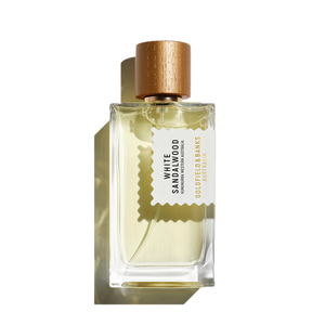 The White Sandalwood 100ml Eau De Parfum by Goldfield & Banks, presented in a clear glass bottle with hints of amber, is adorned with a gold cap and an elegant label, creating a delicate shadow.