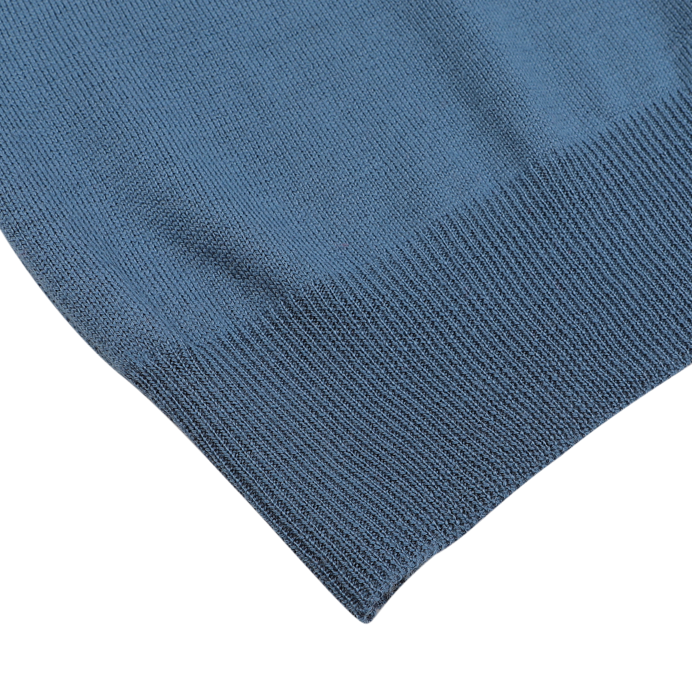 Detailed view of the corner of a Gran Sasso Airforce Blue Extrafine Merino Wool Zip Cardigan resting on a gray surface, showcasing the intricate texture and stitching.