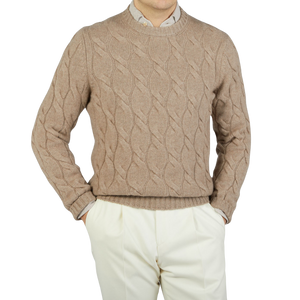 A man wearing a Gran Sasso Beige Cashmere Cableknit Crewneck Sweater and white pants, making a stylish wardrobe choice.