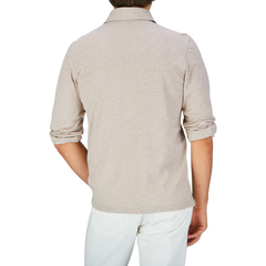 Rear view of a person wearing a Gran Sasso Beige Cotton Jersey Popover Shirt with rolled-up sleeves and white pants.