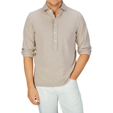 Man in a slim fit, Gran Sasso beige long-sleeve cotton jersey popover shirt and white pants.