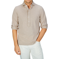 Man in a slim fit, Gran Sasso beige long-sleeve cotton jersey popover shirt and white pants.