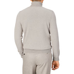 A person is seen from the back, dressed in a beige melange Gran Sasso Pure Cashmere Rollneck sweater and matching pants.