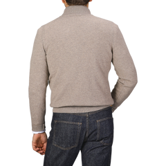 A person wearing a durable and comfortable Gran Sasso Beige Wool Cashmere 1/4 Zip Sweater paired with blue jeans is shown from the back.