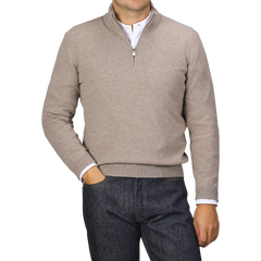 A person wearing a Gran Sasso Beige Wool Cashmere 1/4 Zip Sweater over a white shirt and dark blue jeans stands in front of a plain backdrop.