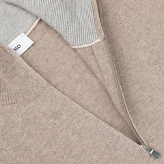 A close-up of a Beige Wool Cashmere 1/4 Zip Sweater by Gran Sasso, showcasing its brown and gray knit texture with a zipper and a tag that reads "LESSO." This durable and comfortable sweater embodies sustainable knitwear values.