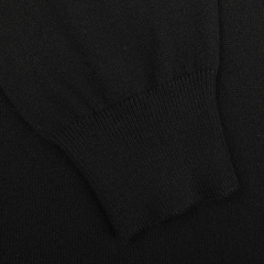 A close-up of the Black Cashmere Crewneck Sweater by Gran Sasso reveals the ribbed cuff and texture, emphasizing its sustainable knitwear crafted from pure cashmere fibers.