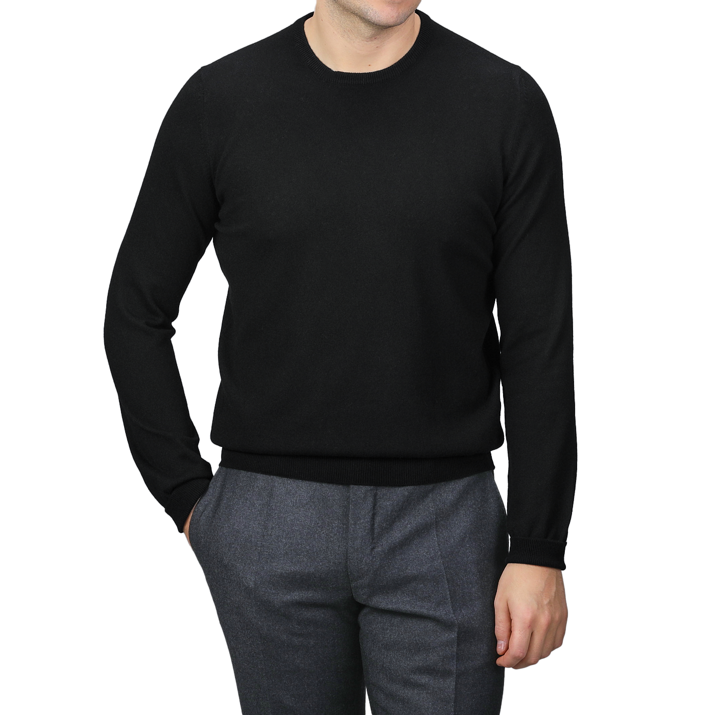 A person wearing the Black Cashmere Crewneck Sweater by Gran Sasso and gray pants stands with one hand in their pocket against a neutral background.