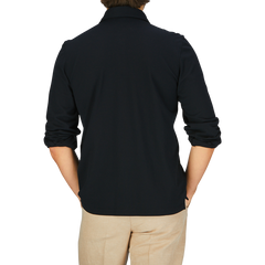 Rear view of a person wearing a black long-sleeve Gran Sasso Black Cotton Jersey Popover Shirt and beige pants.